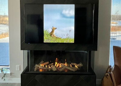 Electric fireplace in a black diamond pattern tile column. TV mounted above.